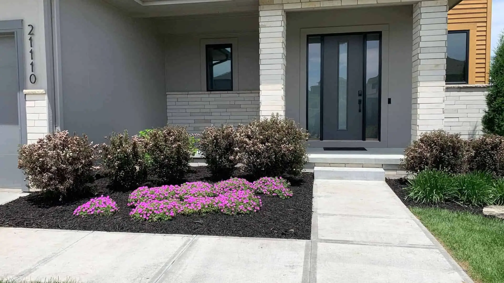 Front Of Home With Flowers And Plants In Fresh Mulch